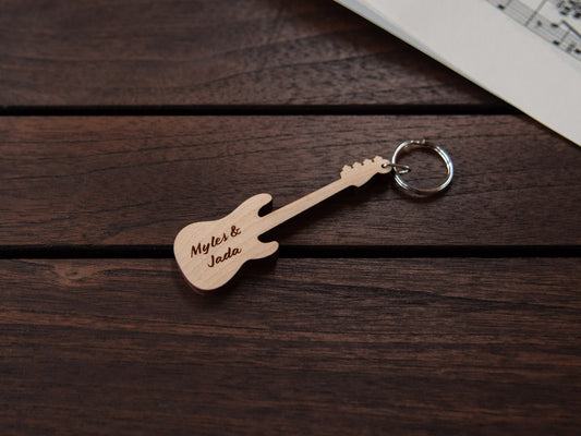 A bass guitar shaped keychain made from maple wood, with personalized engraving