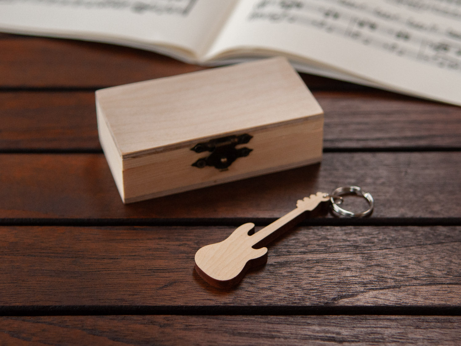 A keychain in the shape of a bass guitar in front of a small wooden box