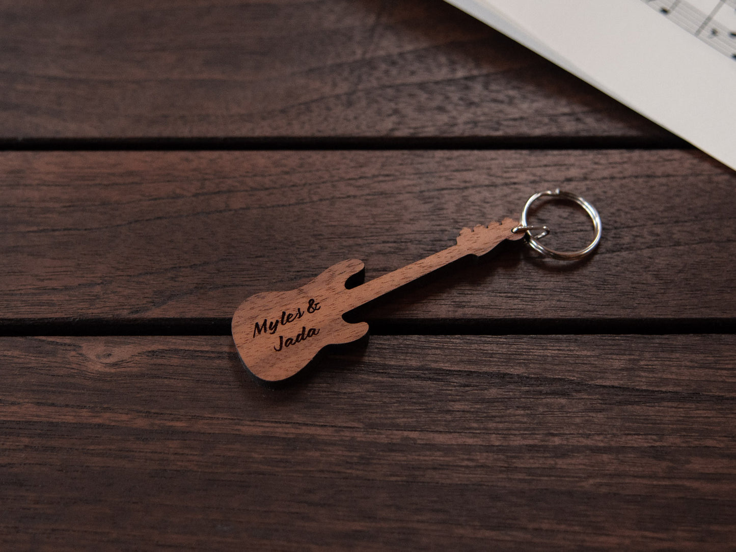 A bass guitar shaped keychain made from walnut wood, with personalized engraving