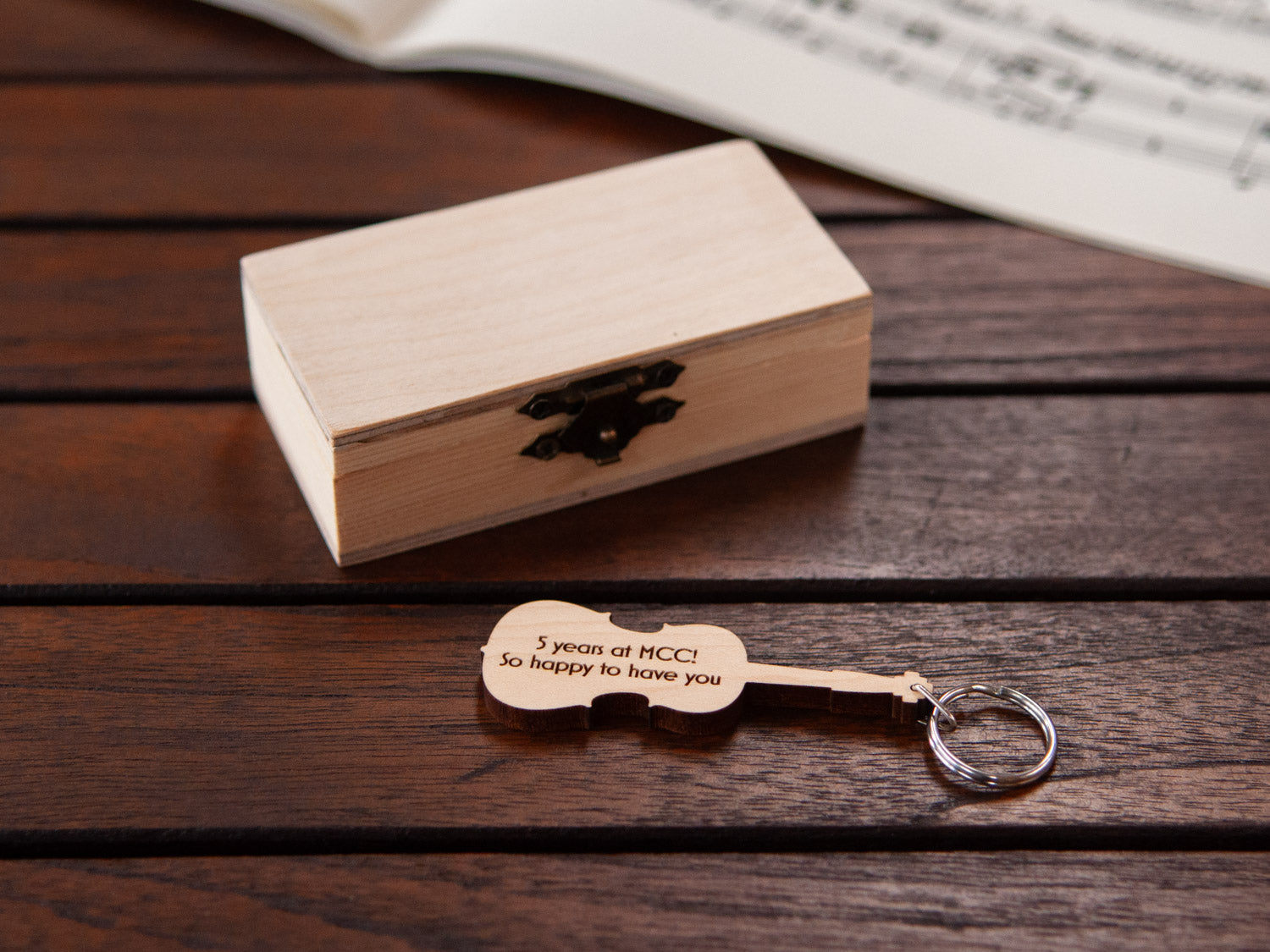 An engraved cello shaped keychain in front of a small box