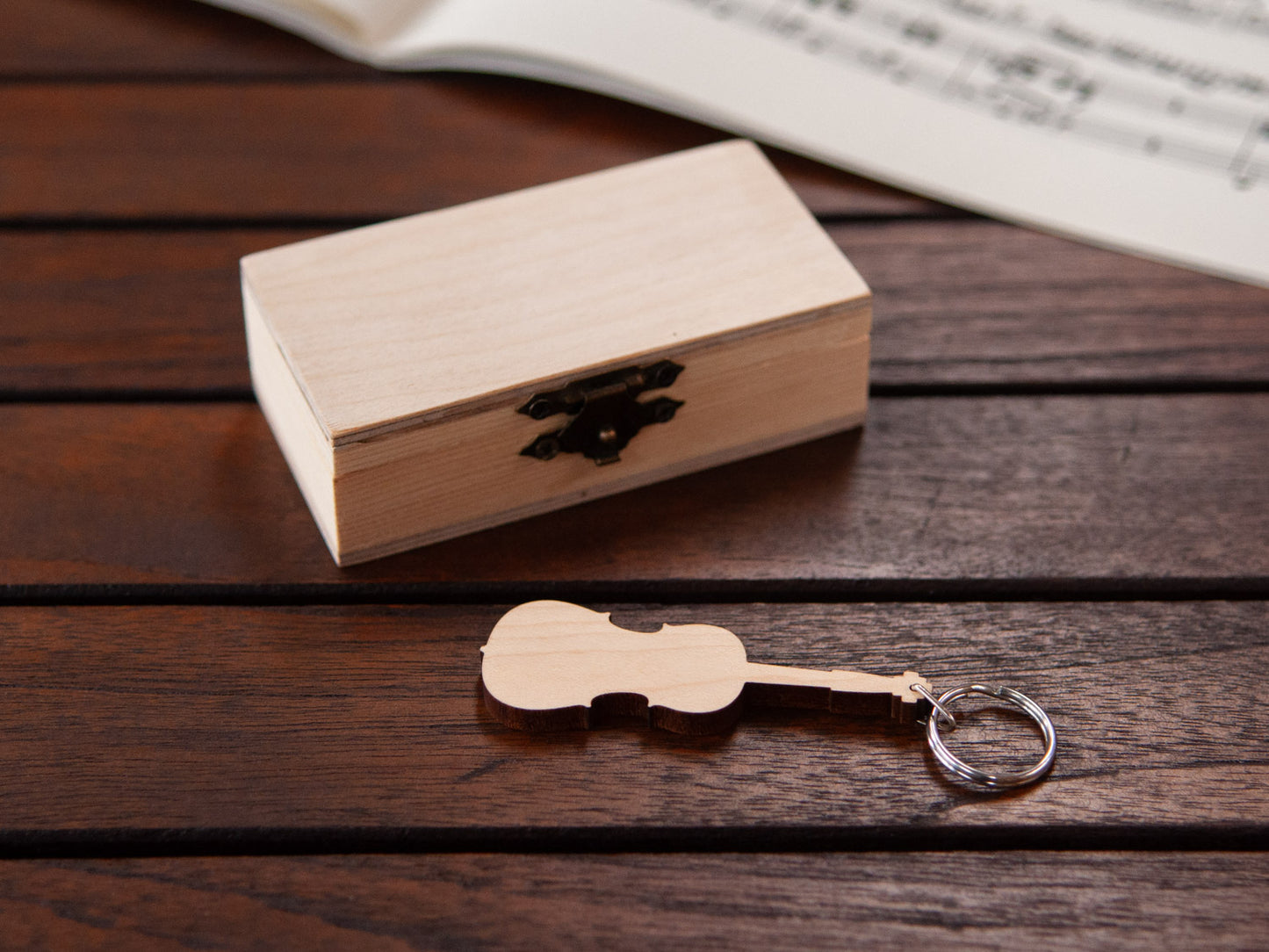 A keychain in the shape of a cello in front of a small wooden box