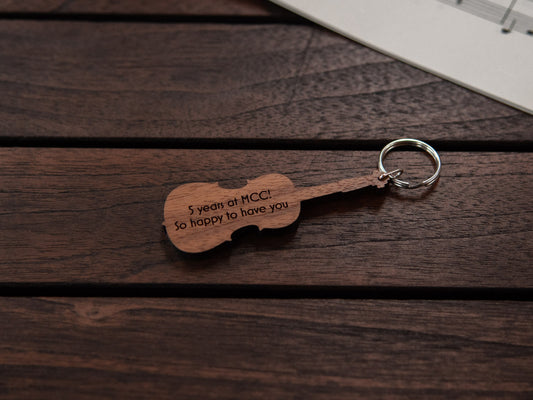 A cello shaped keychain made from walnut wood, with personalized engraving