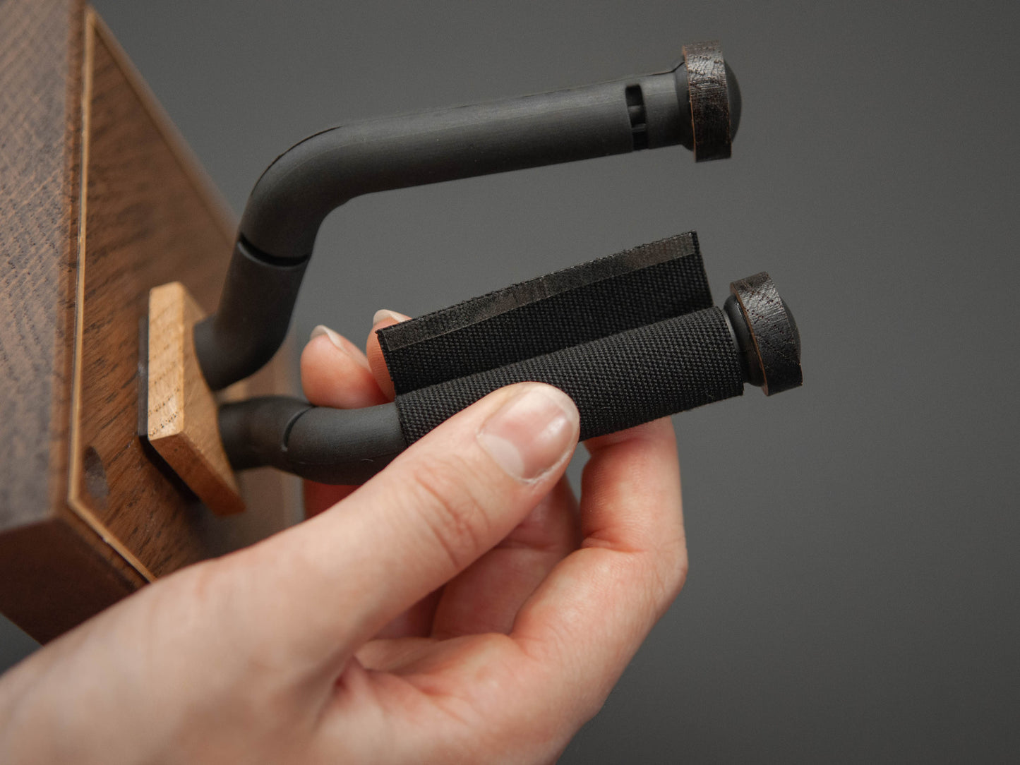 close up of a hand applying a cotton protective pad to a guitar wall mount