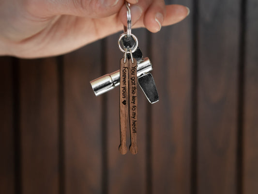 Keychain in the shape of drumsticks with engraving, made from walnut wood. A drum key is also attached to the key ring.