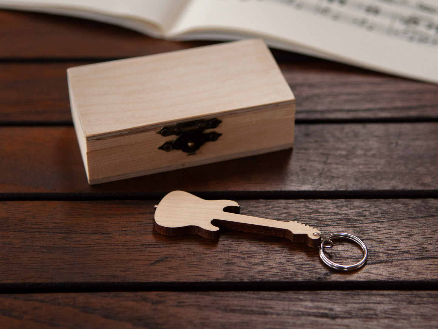 A keychain shaped like an electric guitar in front of a small wooden box.