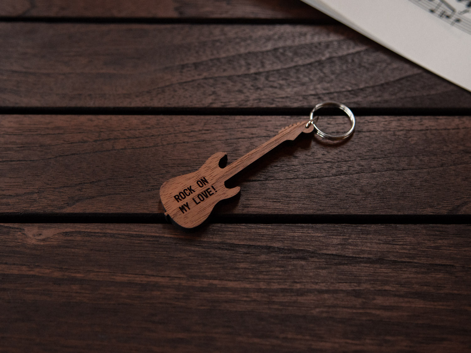 A keychain designed like an electric guitar, crafted from walnut wood, with personalized engraving.