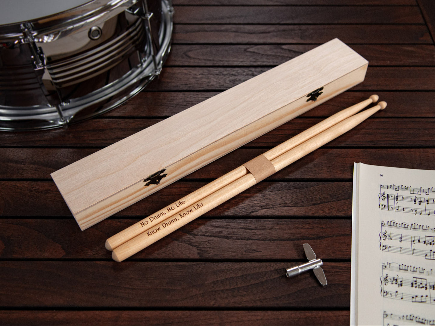 engraved drumsticks made from maple wood, in front of a tailor made wooden box