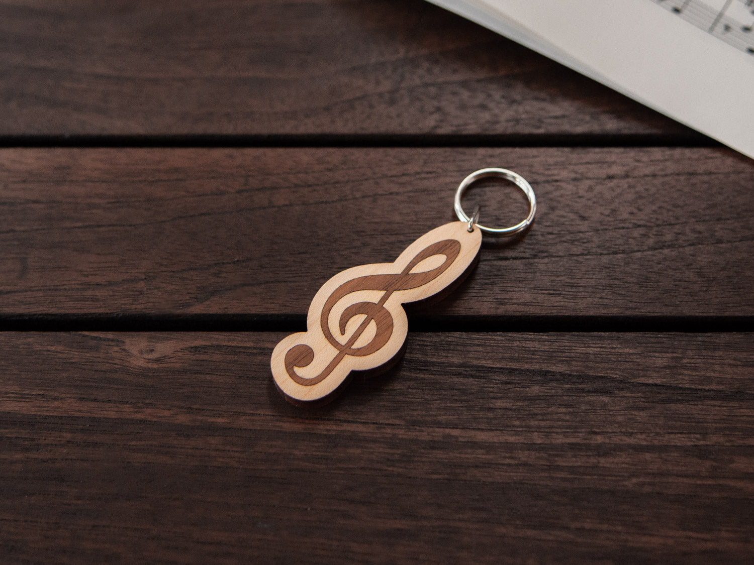 A maple and walnut wood keychain in the shape of a G-clef