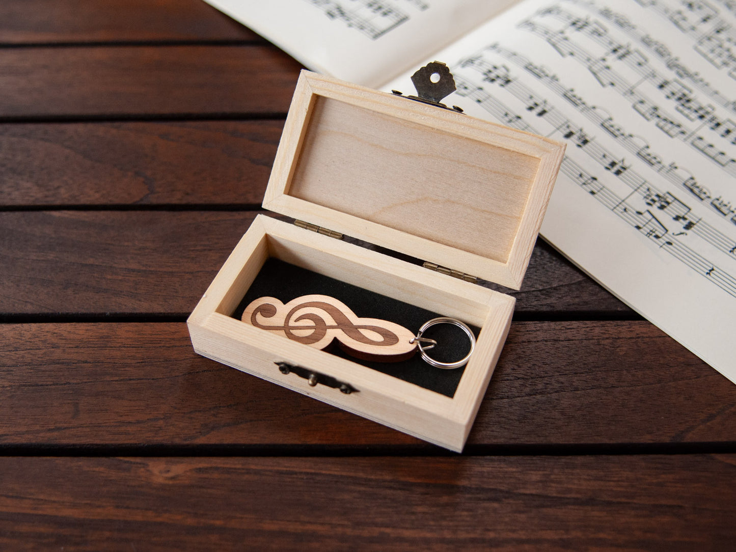 A G-clef shaped keychain placed inside a compact wooden box