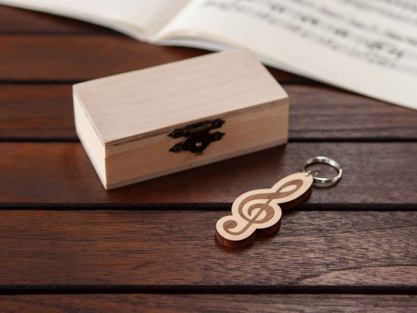 A G-clef keychain positioned in front of a small wooden box.