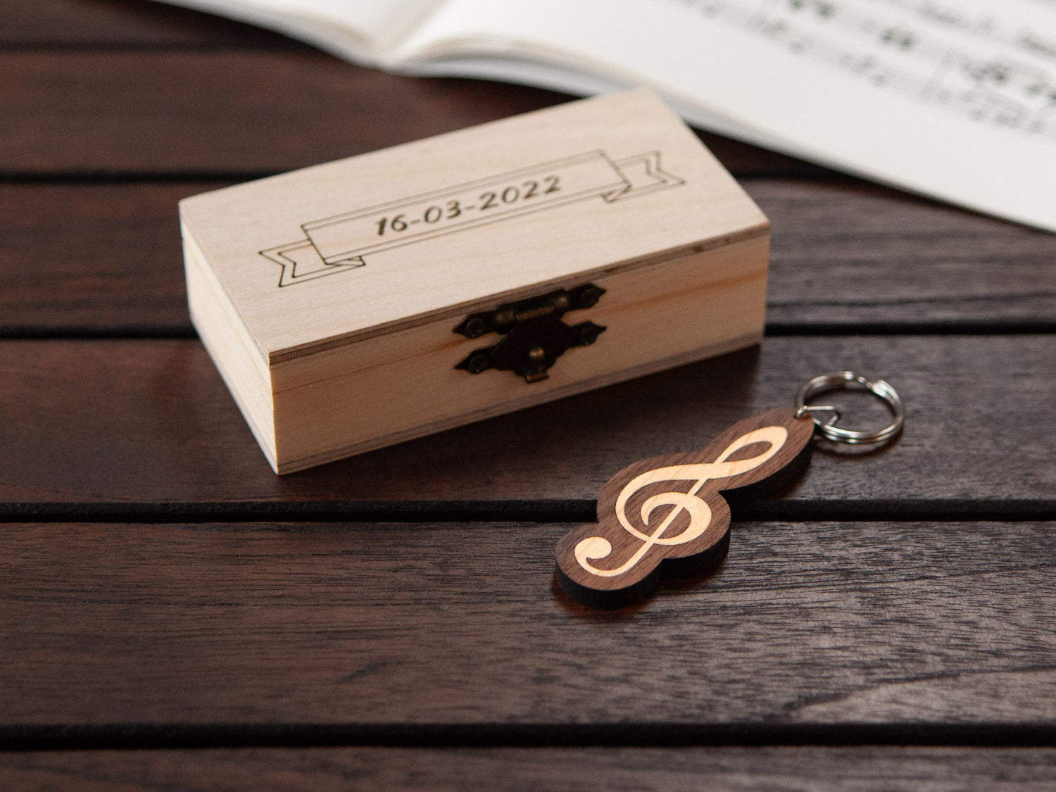 A G-clef keychain positioned in front of a small wooden box.