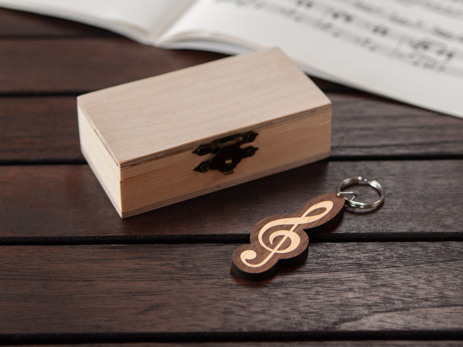 A keychain shaped like a G-clef in front of a small wooden box.
