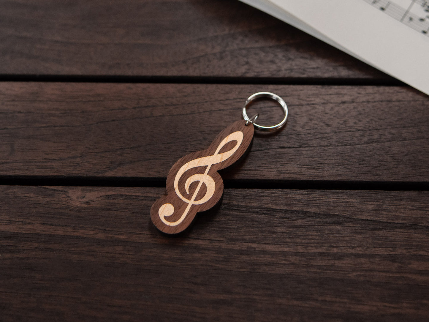 A walnut and maple wood keychain in the shape of a G-clef