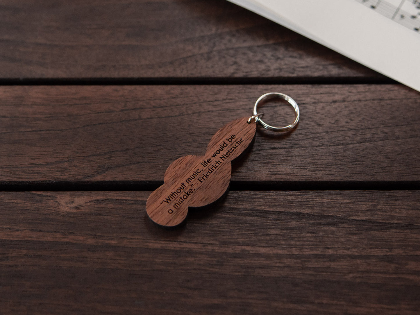 A walnut wood keychain in the shape of a G-clef with personalized engraving