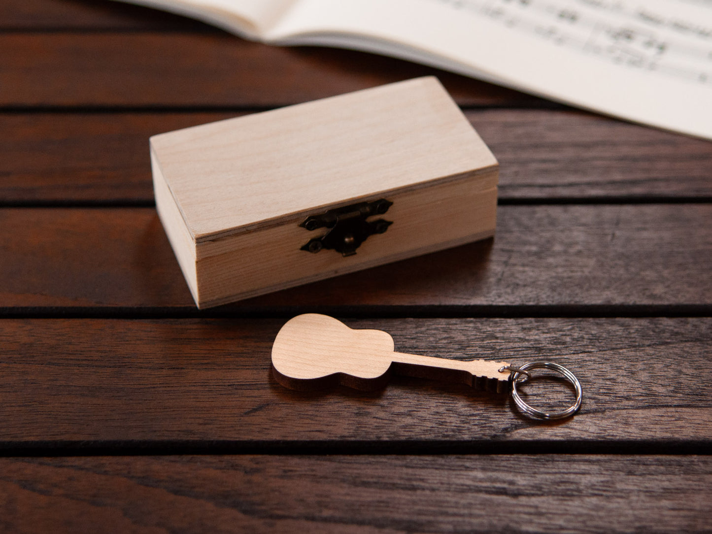 A keychain shaped like a guitar in front of a small wooden box.