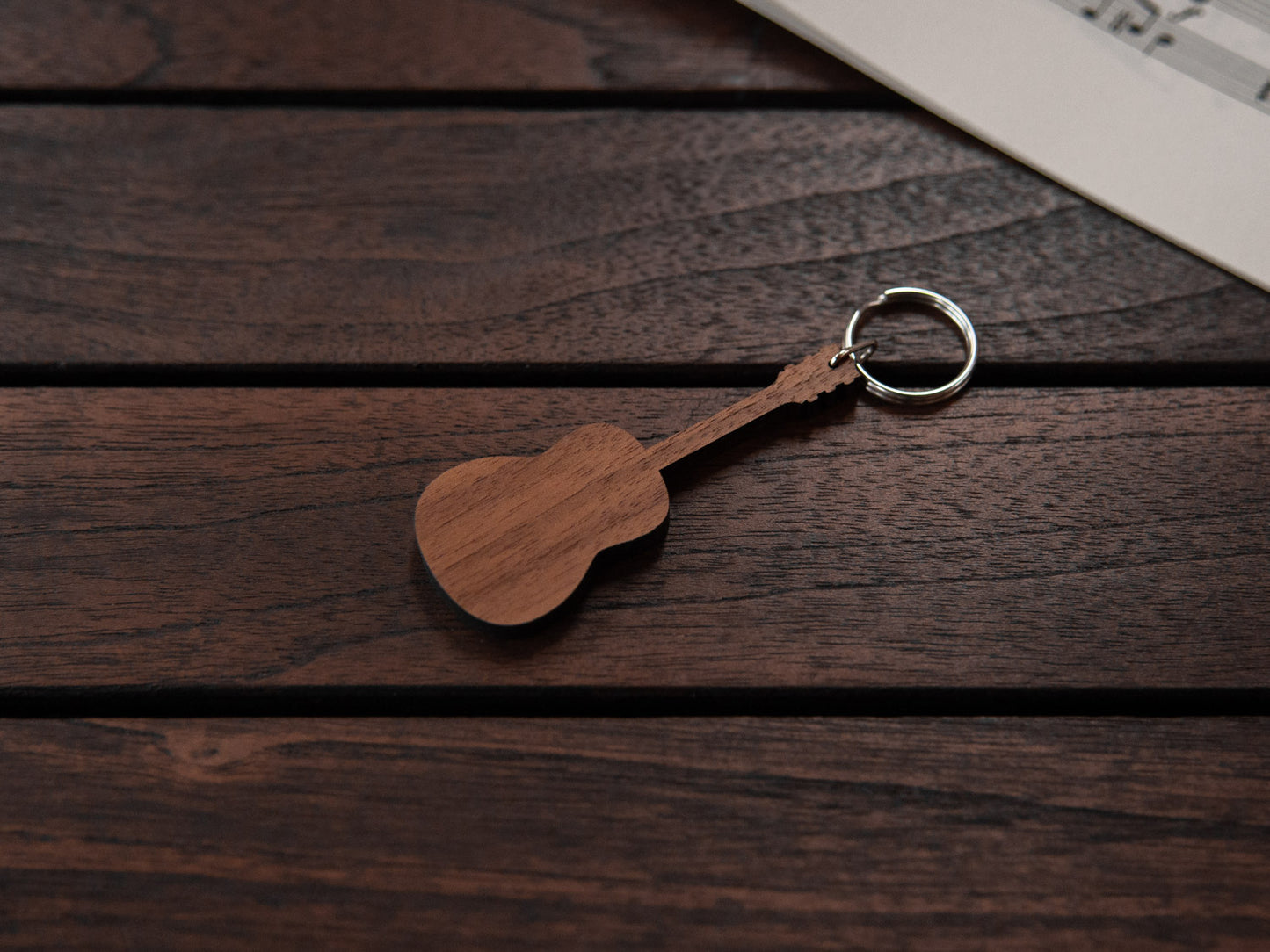 A walnut wood keychain in the shape of a guitar