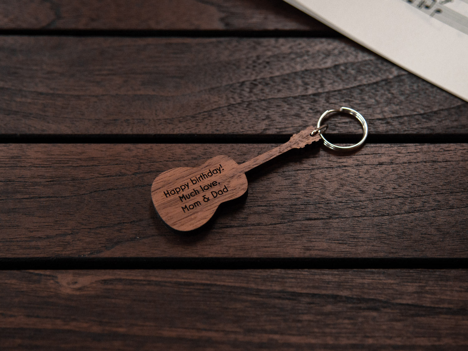 A keychain designed like a guitar, crafted from walnut wood, with personalized engraving.