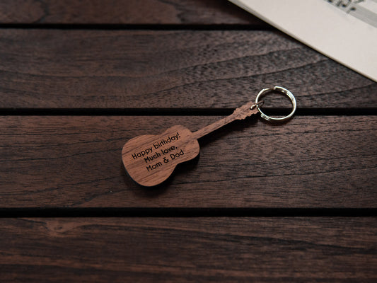 A keychain designed like a guitar, crafted from walnut wood, with personalized engraving.