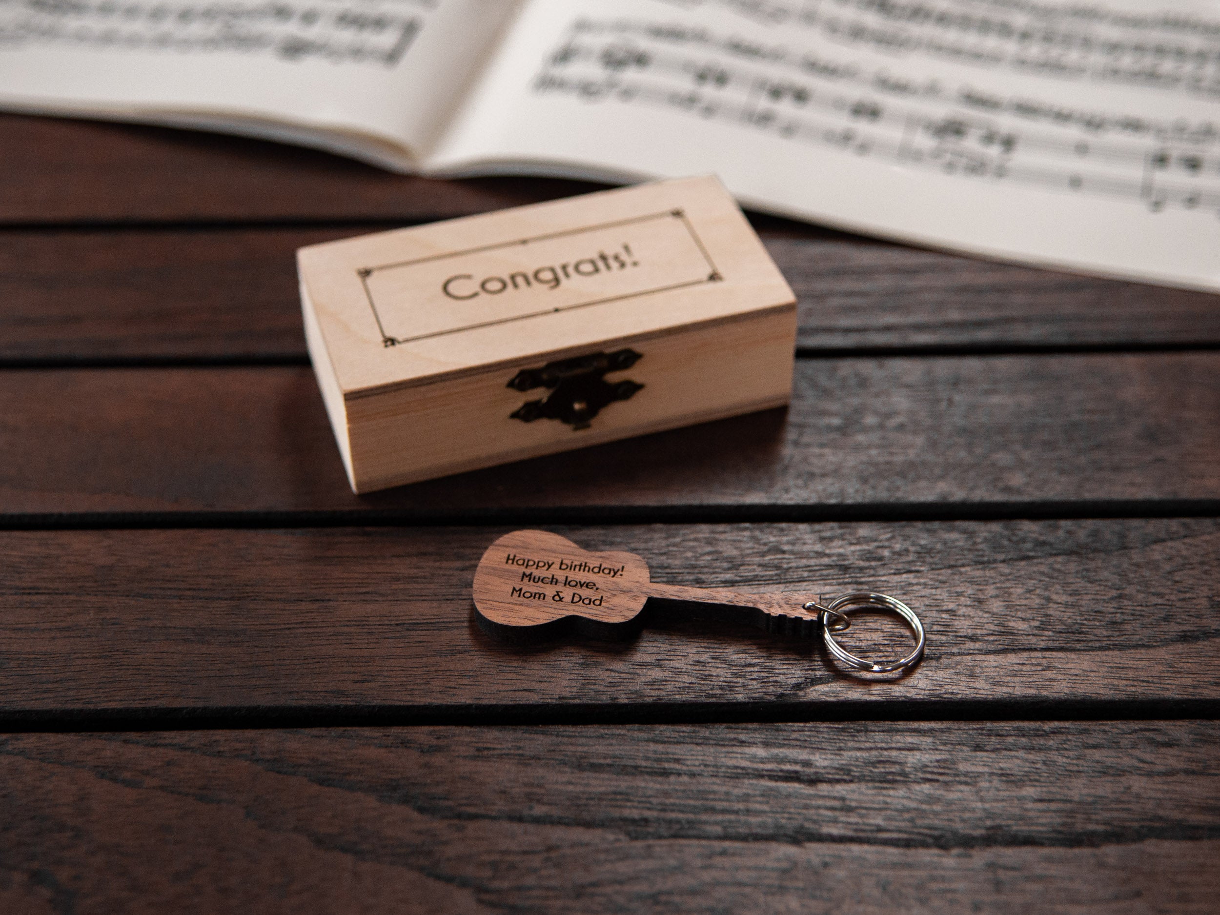 A keychain in the shape of a guitar, made from walnut wood. 