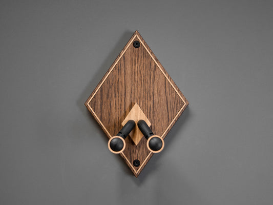 A wooden guitar wall mount in a diamond shape. The body is made from darkened oak, with contrasting light oak strips on the border