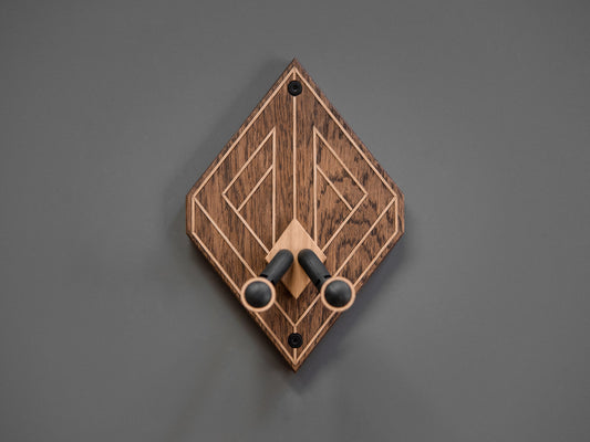 A guitar wall mount, made from dark stained oak wood. Light oak strips create a optical illusion effect.