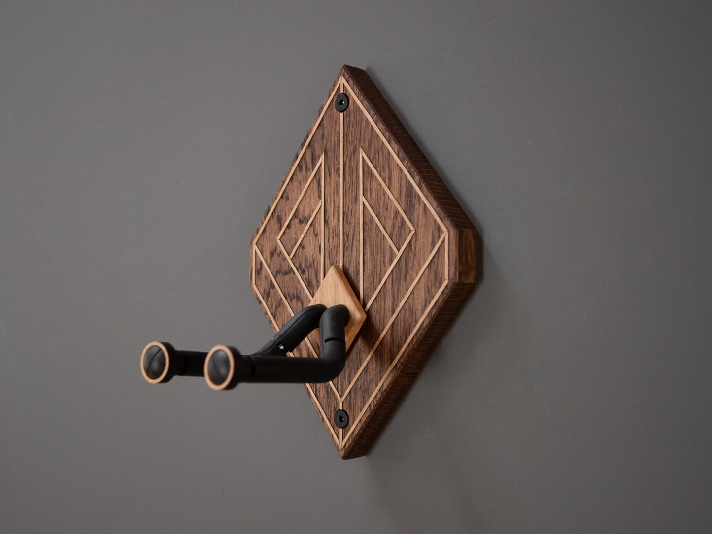 Side view of a guitar wall mount, made from dark stained oak wood. Light oak strips create a optical illusion effect.