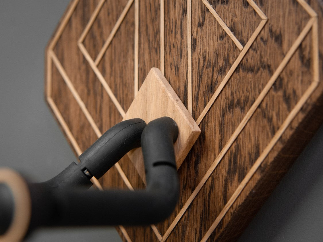 Close up shot of a wooden guitar wall mount, with light oak details