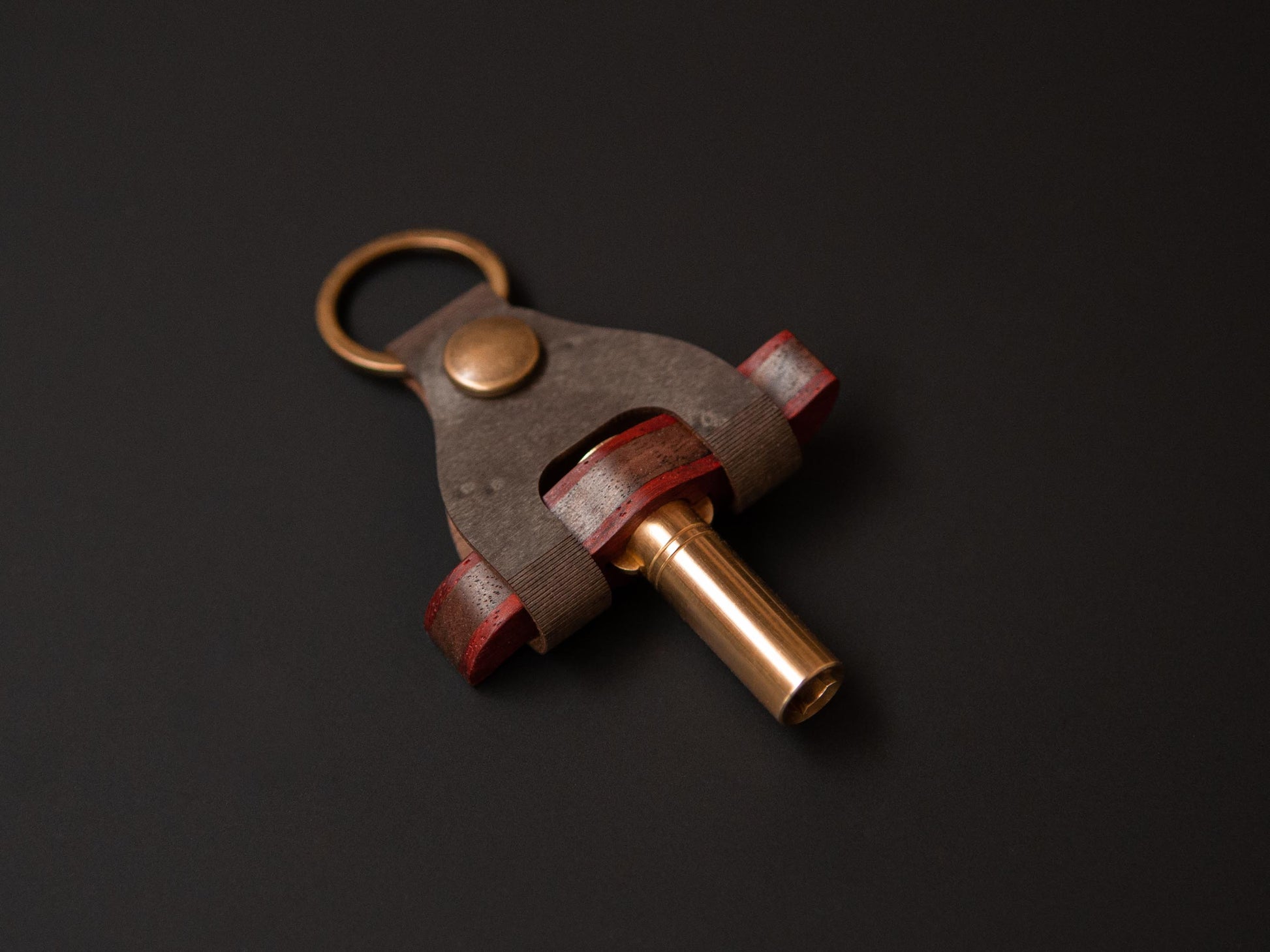 A handcrafted drum key made from walnut, padauk and brass in its tailor made case