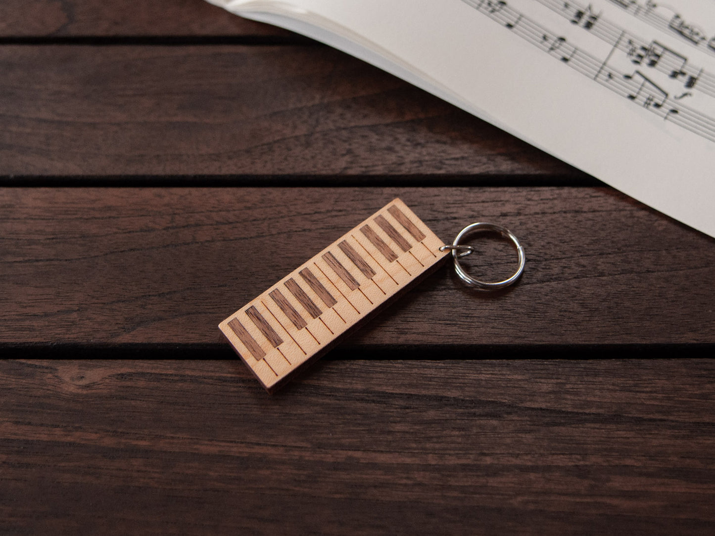 A keychain designed like a the keys of a piano, crafted from maple and walnut wood, with personalized engraving.