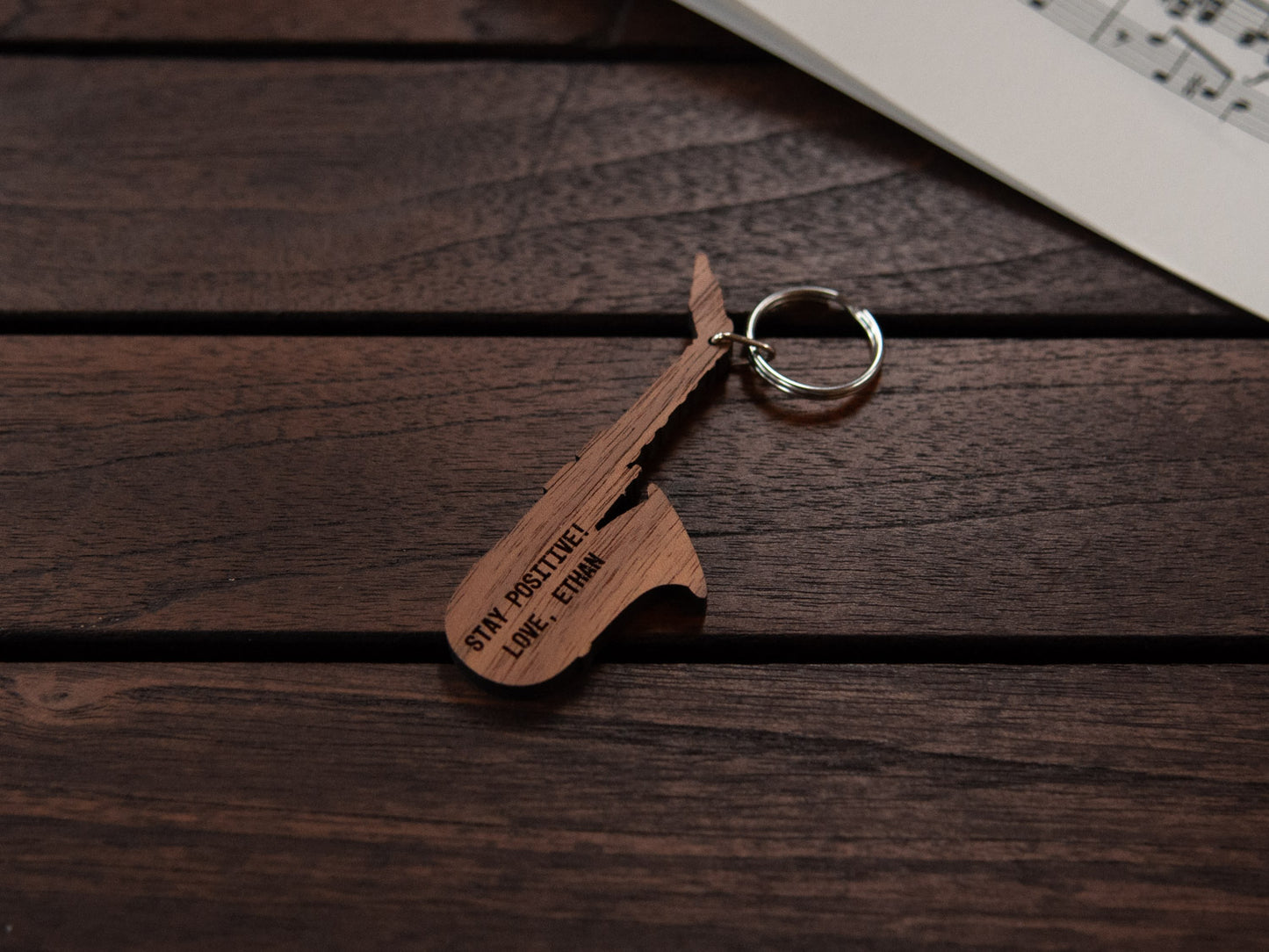 A keychain designed like a saxophone, crafted from walnut wood, with personalized engraving.