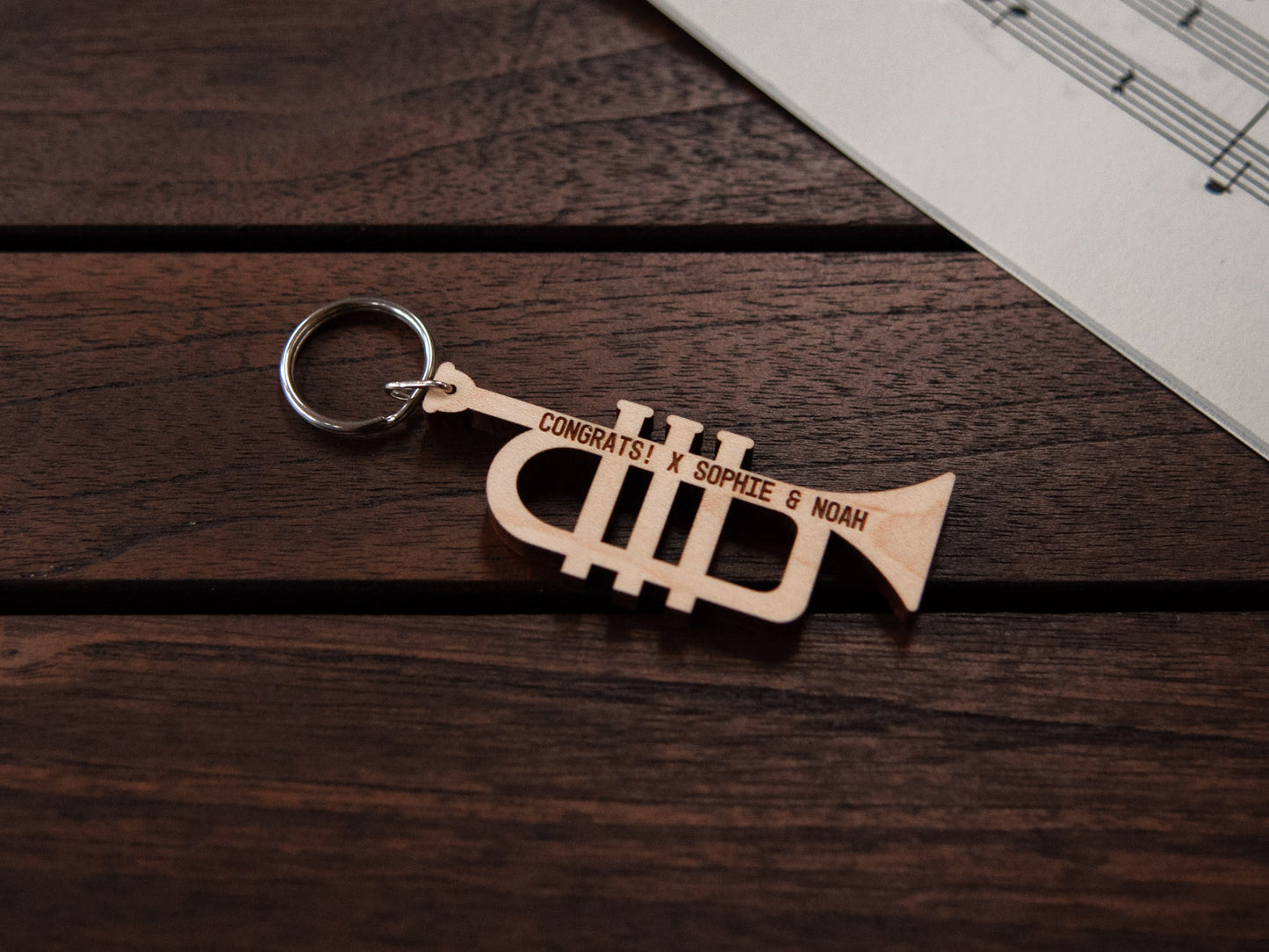 A keychain designed like a trumpet, crafted from maple wood, with personalized engraving.