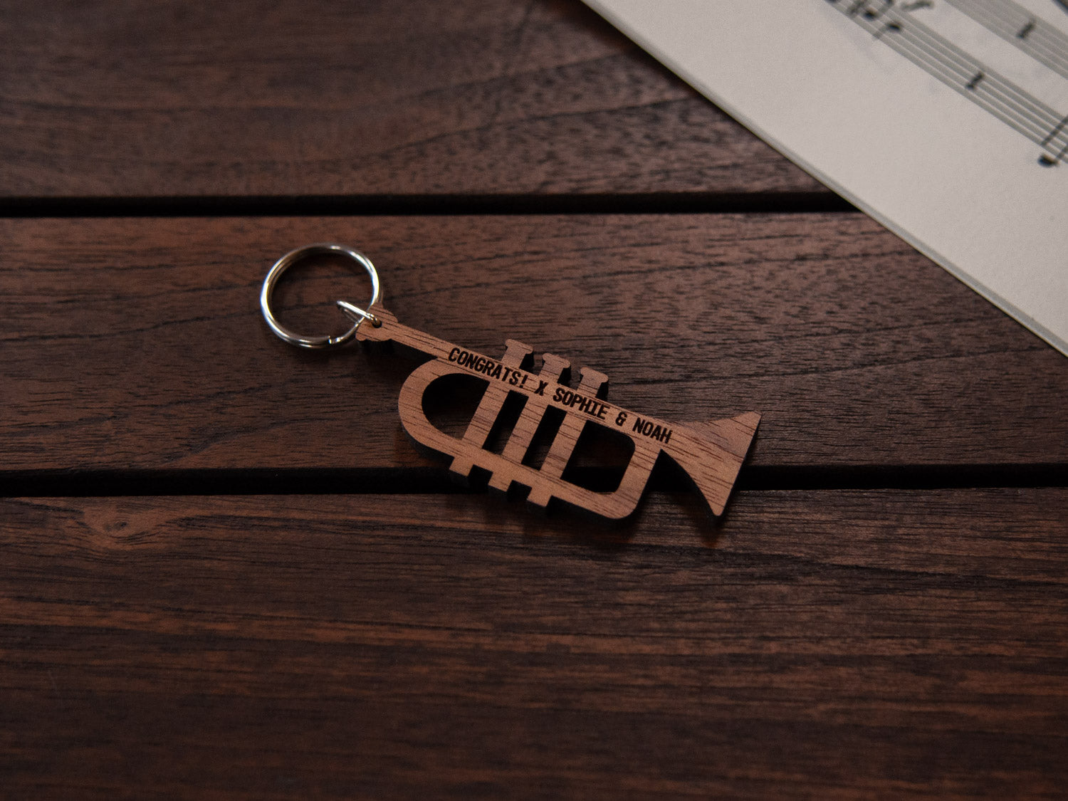 A keychain designed like a trumpet, crafted from walnut wood, with personalized engraving.