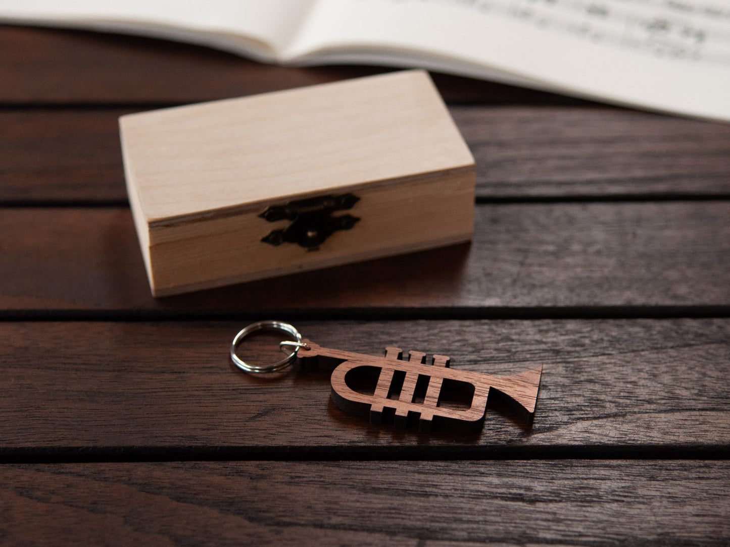 A trumpet keychain positioned in front of a small wooden box.