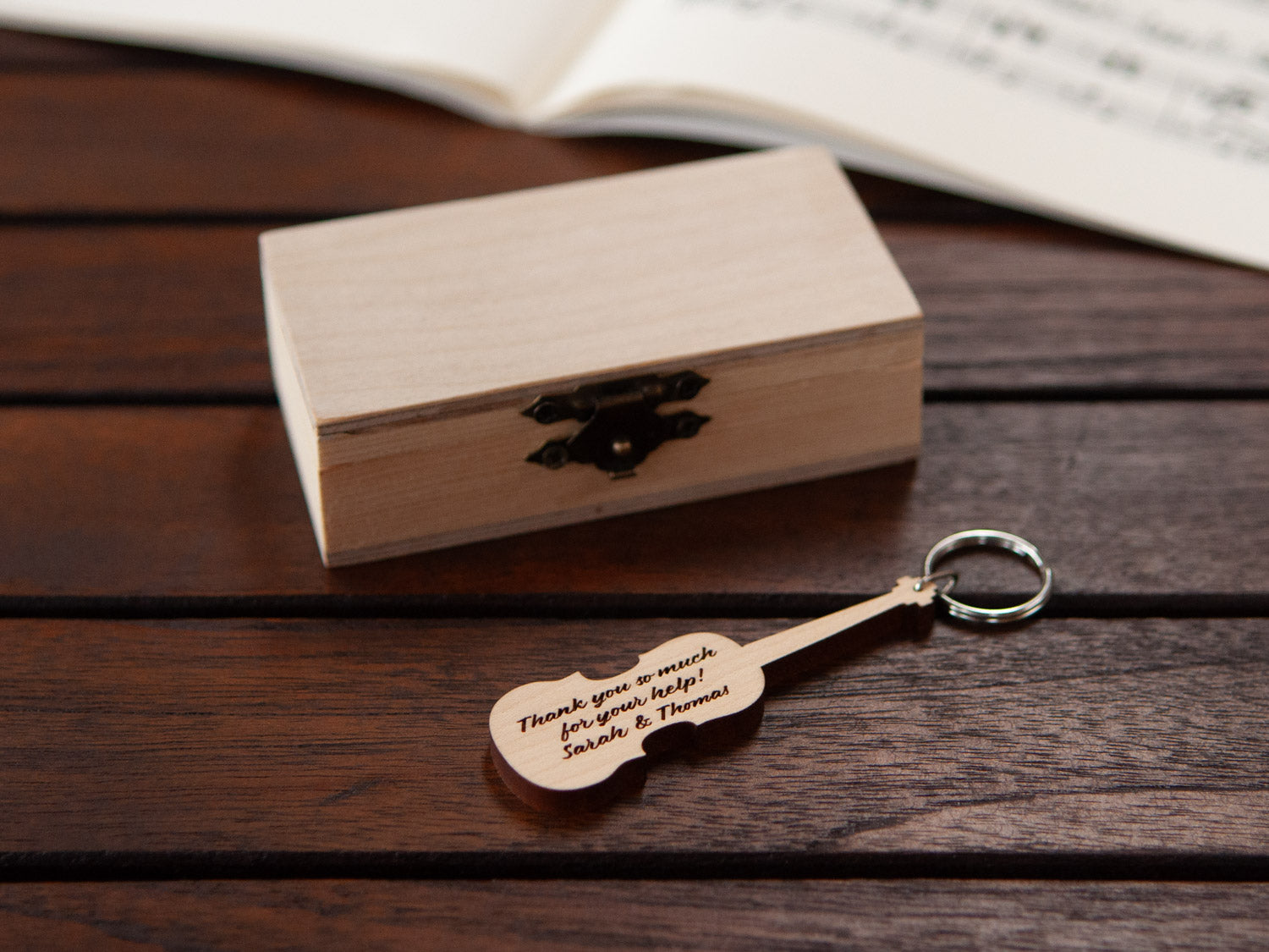 A personalized violin keychain positioned in front of a small wooden box.